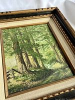 Close-up view of painting signature and tree details