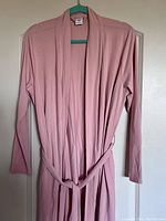 Full view of the pink Smash + Tess robe hanging on a hanger against a door to show length and fit.
