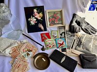 Full lot overview showing all items including artwork, gloves, wallets, photographs, books, tray, bell, glass bottle, and ephemera.