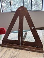 Front view of vintage wooden easel with triangular frame, showing wear and paint splotches.
