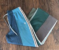 Front view of the Adidas wide leg pants showing the colour-block design with blue, green, and grey panels, Adidas logo and three stripes on one leg, elastic waistband with drawstring.