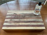 Butcher block cutting board and cutting board oil bottle on wooden table with natural light from window.