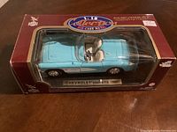 Blue 1957 Chevrolet Corvette 1:18 scale die-cast model car in original red and clear display box, showing top view with detailed interior.