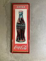 Front view of framed Coca Cola bottle artwork, showing red frame and classic bottle illustration.