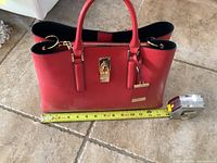 Red Alto handbag approximately 10 inches wide, showing front with handle and lock detail with measuring tape.