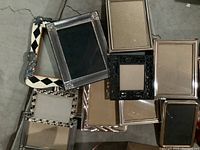 Multiple assorted picture frames in different sizes and styles arranged together.