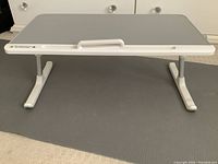 Front view of portable lap desk showing adjustable legs and flat work surface.