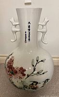 Full view of white ceramic floor vase showing cat-shaped handles, and floral and bird paintings on the bulbous base