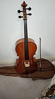 Full upright view of cello on soft case with bow leaning