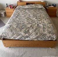 Full frontal view of the bed, showing the wooden frame, headboard shelves, and comforter on the bed.
