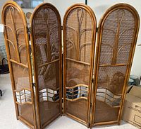 Front view of 4-panel rattan room divider showing woven cane design and decorative curved rattan supports