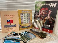 Image showing Republic of China official postage stamp collection folder, Taiwan commemorative stamps, multiple postcards, Disney pens, and Georgia Straight magazine.