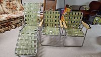 Three vintage lawn seating pieces group: two green woven fabric lawn chairs with wooden armrests, and one matching lounger with metal frame.