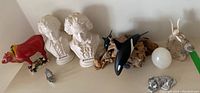 Full view of all items including busts, bull, killer whales, stone egg, stone bird, metal tiger, and ship clock on shelf
