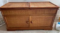 Front view of the wicker cabinet showing the two woven wicker top panels and two front doors with wood framing and round knobs.