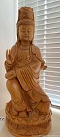 Full front view of the 16 inch tall carved wood Asian statue showing seated figure against a blind.