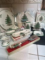 Overview of the 12-piece Spode Christmas Tree bone china accessory set including trays, fork, napkin and tea accessories all decorated with the Christmas Tree pattern.