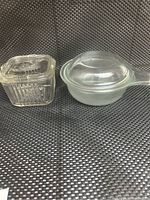 Photo showing vintage Federal clear glass square ribbed refrigerator dish with matching lid and Pyrex clear glass saucepan with handle and lid.