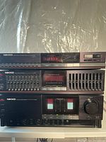 Three stacked units: NT100 tuner on top, EQ100 equalizer in middle, NA100 amplifier at bottom