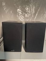 Pair of Polk bookshelf speakers with black fabric grille covers, wood-grain finish on sides and top.