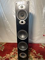 Full view of the Polk RTi A7 speaker showing four drivers and ports on black wood grain finish.