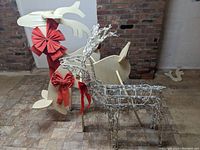 Two white wooden reindeer with red bows displayed against brick and tiled floor alongside a wire-frame reindeer