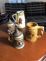 Photo of four mugs and steins on wooden table with couch background
