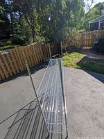 Side-angle view showing the three wire shelves and chrome poles in outdoor sunny setting.