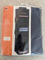 View of the original packaging showing the 6 shelf sweater organizer in black fabric with some shelves holding folded items.
