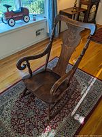Full side and front views of the antique rocking chair showcasing inlaid wood backrest and carved details on arms and legs.