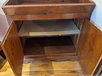 Open cabinet showing interior shelf and storage space inside the antique dry bar.