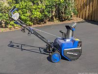 Side view of blue SnowJoe electric snowblower with power cord, showing wheels, handle, and chute