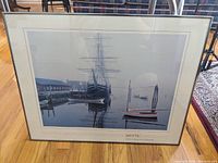 Photo of the framed Mystic Seaport print showing the large ship docked at Mystic Seaport with smaller boats and harbor details.