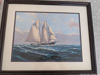 Framed print of a sailboat at sea with waves and sky, in a wooden frame and white mat with black border