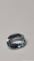 Oval cut soft blue aquamarine gemstone with clear VS clarity and high luster, photographed against a plain background.