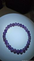 Front view of purple dream amethyst stretchy bracelet formed by round beads with glossy finish, displayed in circular shape.