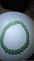 Top view of the green aventurine bead stretchy bracelet, showing smooth, round polished beads in soft green color on a stretchy cord.