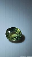 Clear detailed image of oval cut mint green sapphire stone on a flat surface showing color and clarity characteristics.