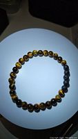 Tiger eye and lava stone stretchy bracelet on white circular display with lighting highlighting bead colors and textures.
