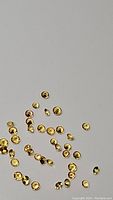 Scattered small round yellow sapphires on neutral background showing diamond faceted cut and yellow color.