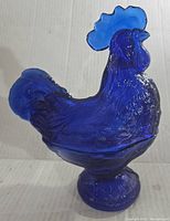 Side profile view of the cobalt blue glass hen figurine showing detailed texture and shape.