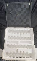 Glass chess set with board and clear glass chess pieces in white foam packaging