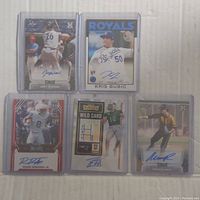 Five sports trading cards with visible autographs in protective sleeves.