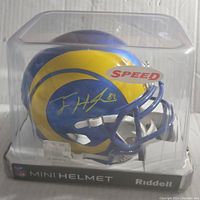 Mini helmet in clear plastic display box showing blue and yellow Los Angeles Rams design and Tyler Higbee autograph in silver.