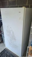 Full view of the white Kenmore deep freezer showing wear marks on the front door.