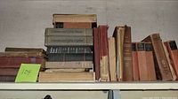 Shelf with several stacked and upright vintage books in various conditions and colors.