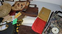 Arrangement of vintage purses including brown suede-like handbag with patches, round woven straw bag, red clutch, white and yellow small purses, and black fabric purse with mirror.