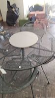 Full view of round wrought iron patio table and two chairs, showing mesh construction and black finish.