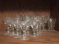 Set of stemmed crystal glasses with carved patterns arranged on wooden shelf