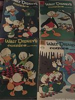 Four vintage Walt Disney comics with colorful covers featuring Donald Duck and nephews with some wear and spine damage visible
